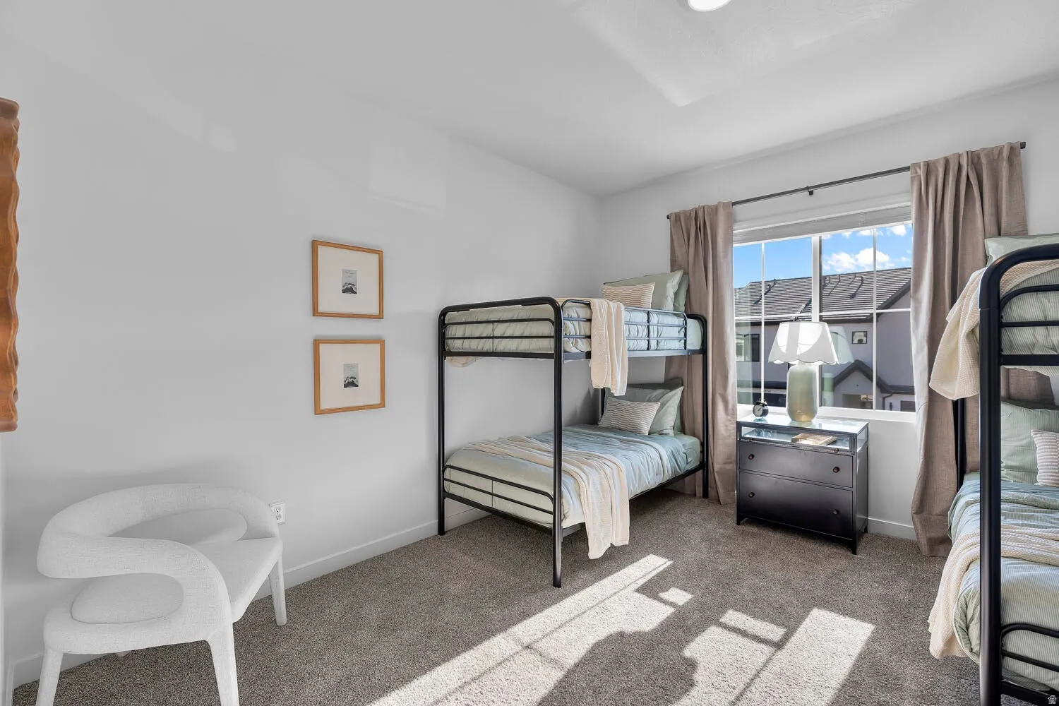 Neutral-toned carpeting, white walls, and a large window with neutral drapery