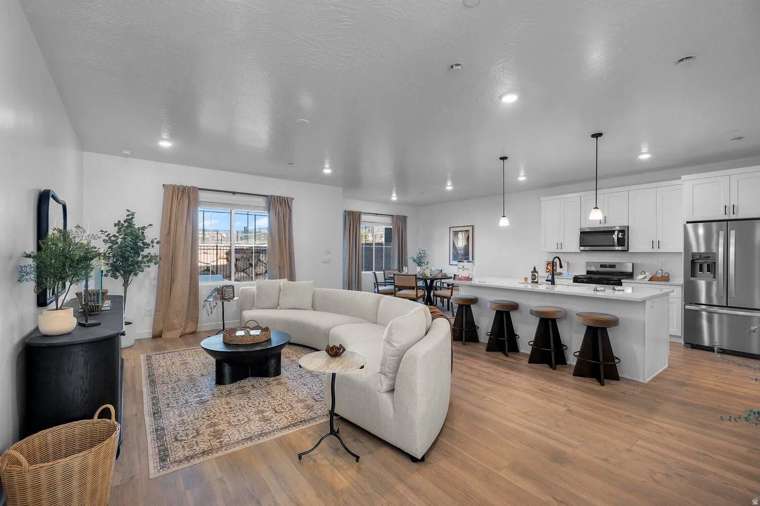 Open-concept living space with wood-finish flooring, recessed lighting, and a kitchen island with pendant lighting