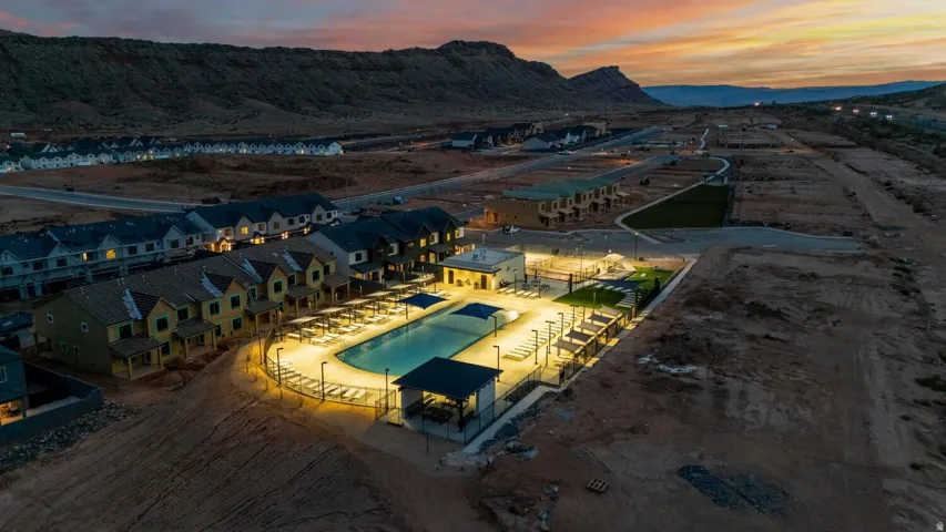 Community swimming pool with surrounding lounge seating, multiple covered pergolas, and adjacent green space
