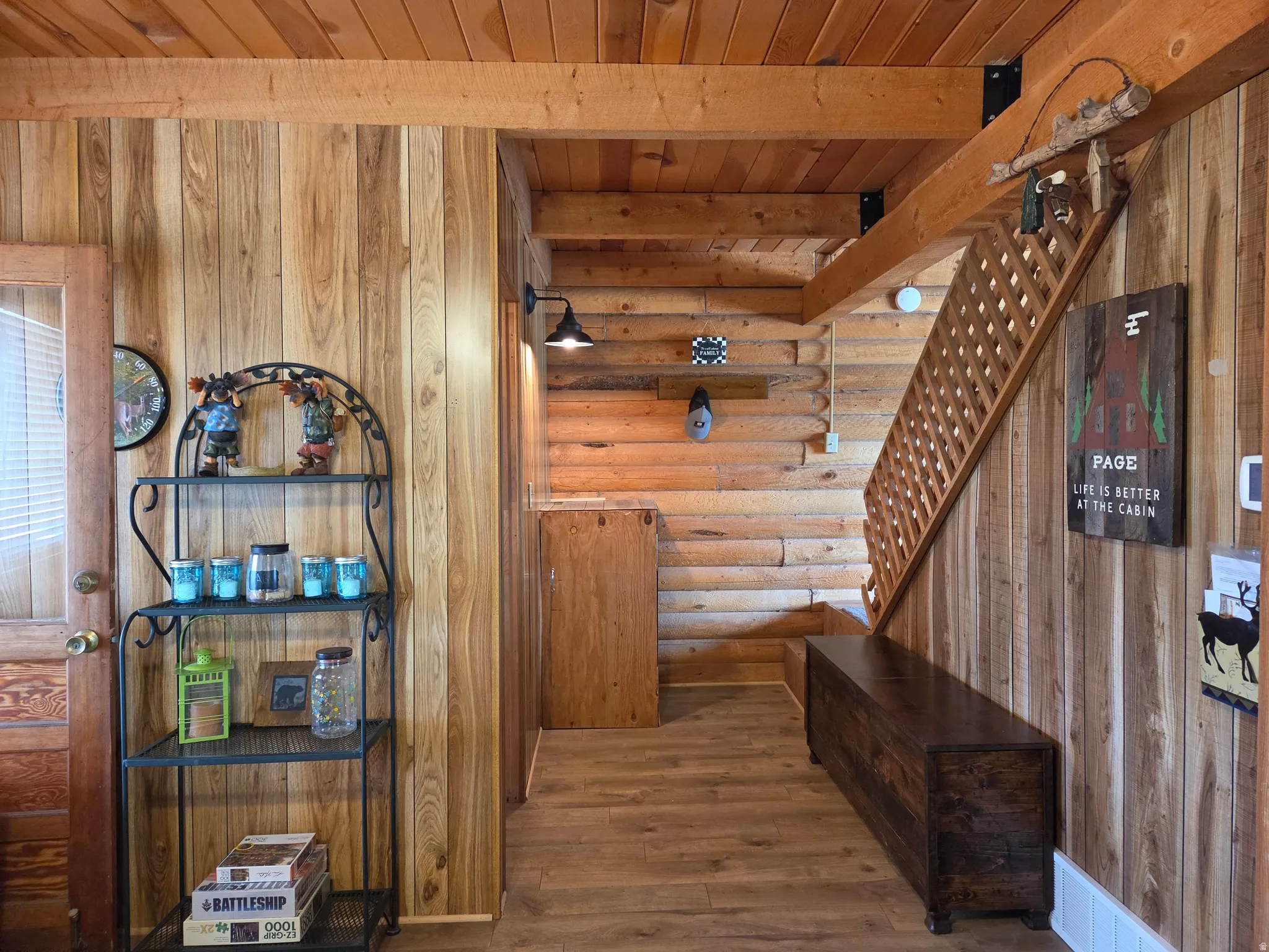 Wood-finish flooring, wood paneling, wood-beam ceiling, wood staircase with lattice balusters, and a wooden storage bench