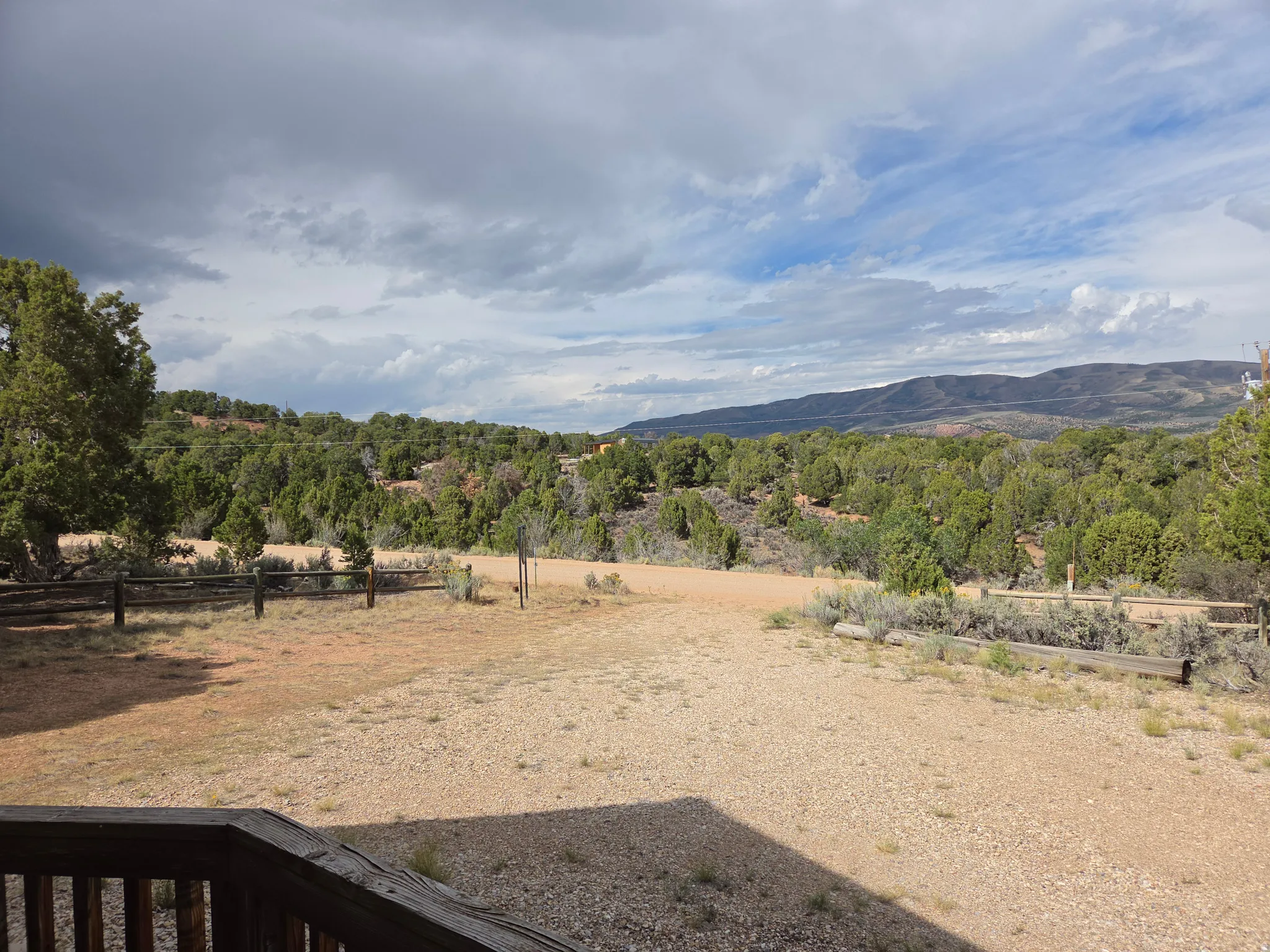 Expansive landscape featuring mature trees, distant mountains, and a wood-finish fence