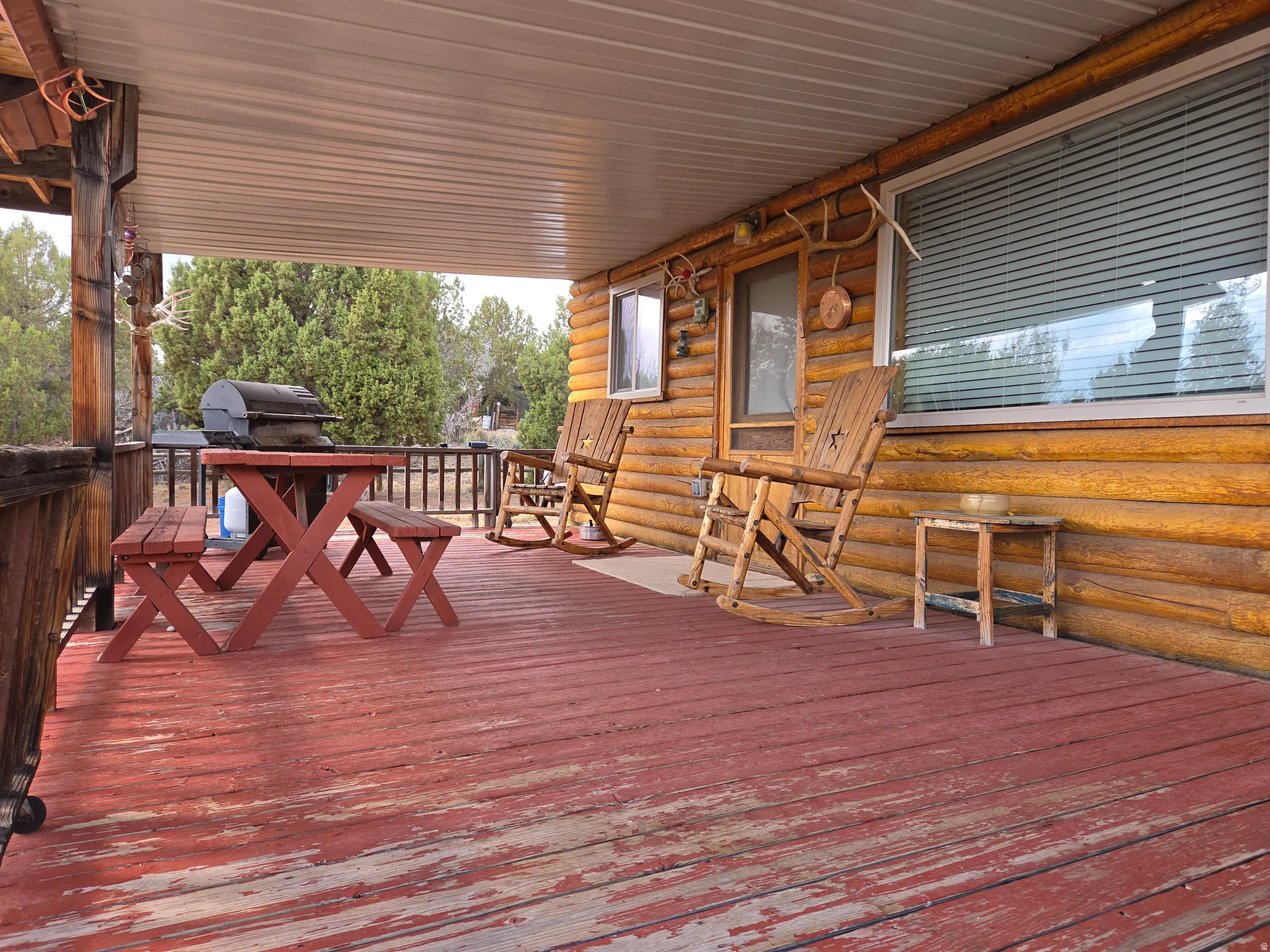 Expansive covered porch featuring a wood-finish exterior, wood railing, and plank flooring