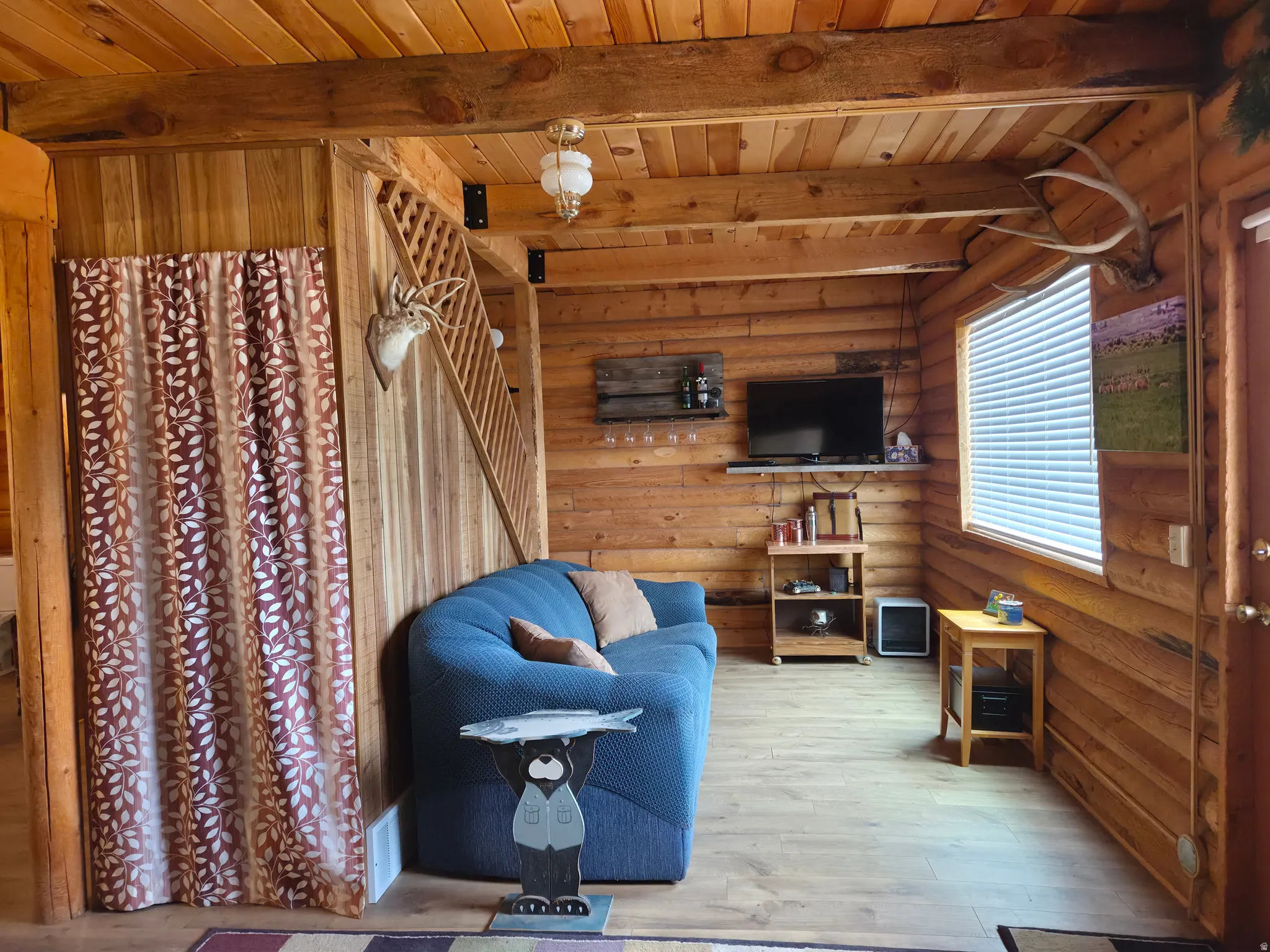 Wood-finish flooring, wood-paneled walls, exposed wood beams, and a wood staircase with lattice railing