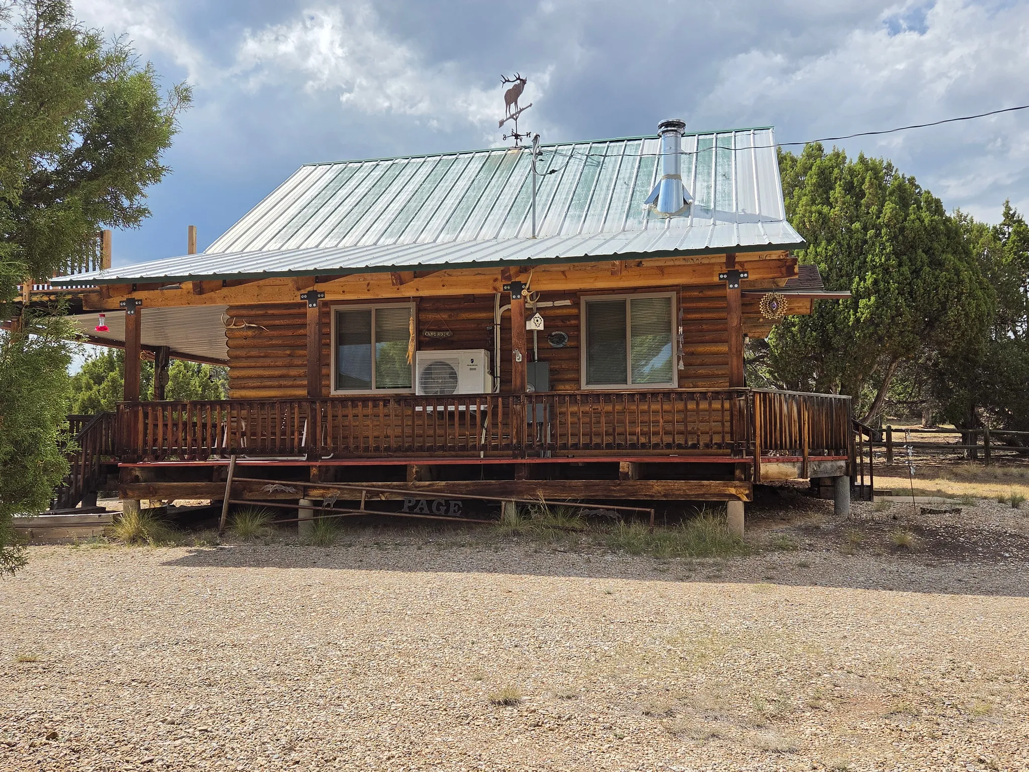 Log cabin style exterior featuring a covered porch, metal roof, and wood railing