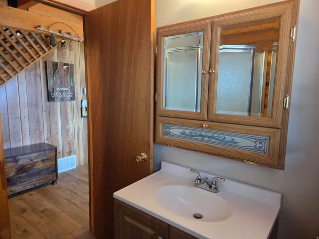 White vanity with integrated sink, chrome faucet, and wood-finish cabinetry