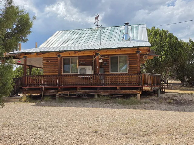 Log cabin style exterior featuring a covered porch, metal roof, and wood railing