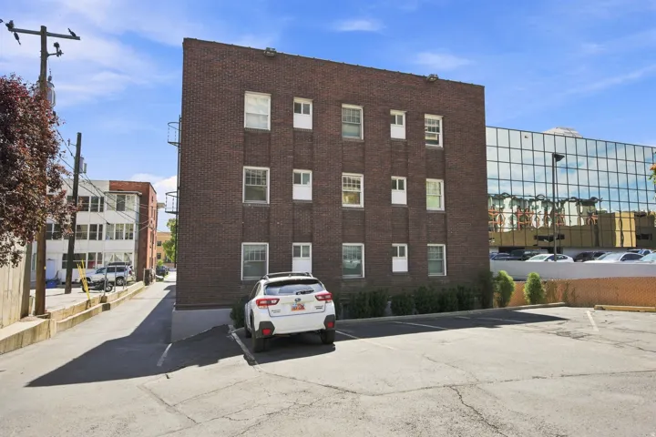 Brick exterior building with multiple windows and an adjacent paved parking area