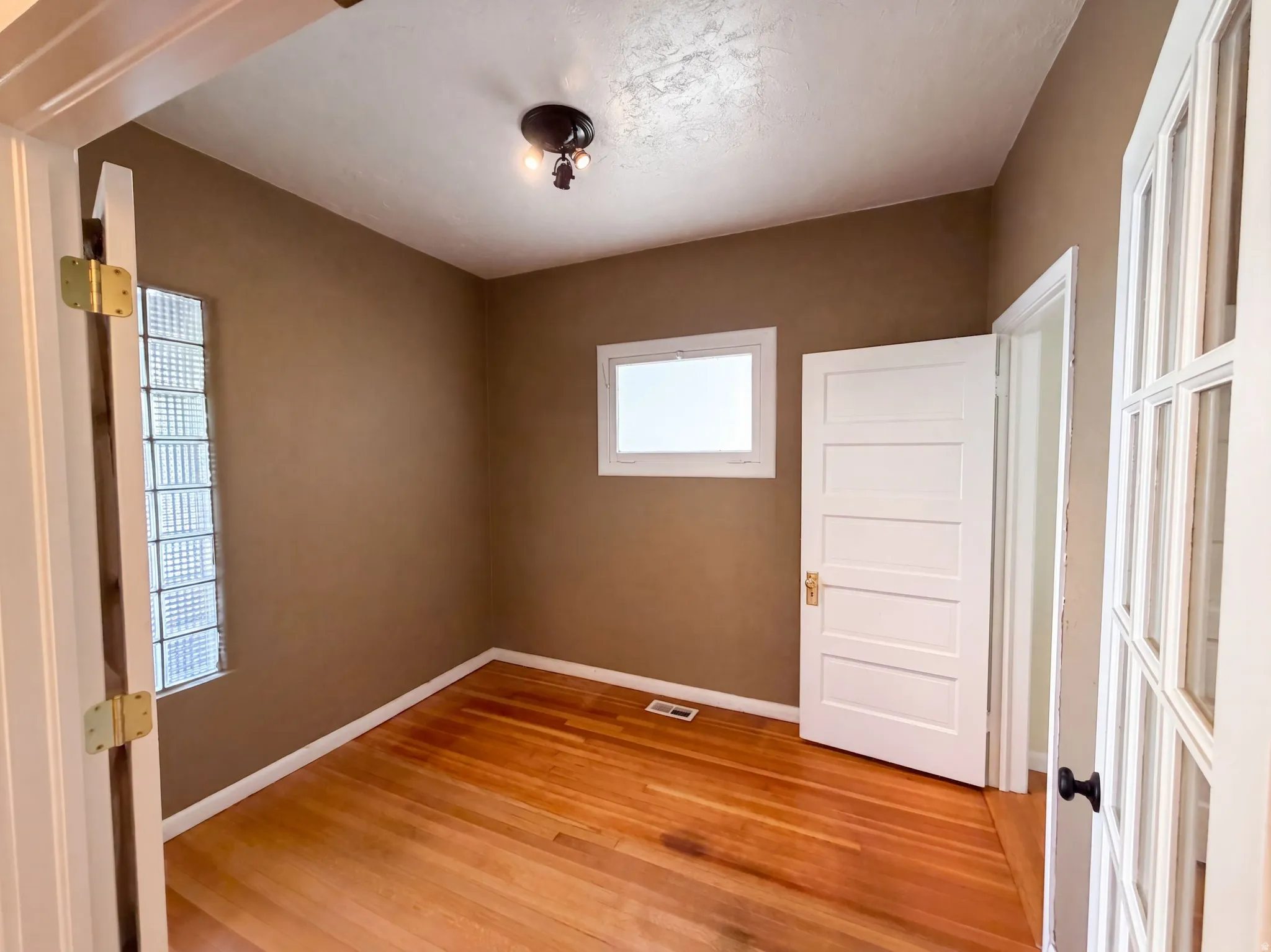 Hardwood flooring, glass block window, white trim, five-panel interior door, and French doors