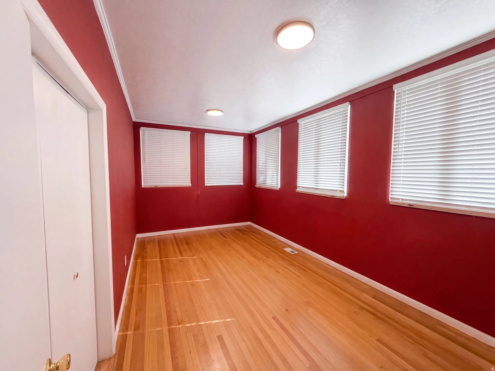 Hardwood flooring, multiple windows with blinds, flush-mount lighting, and bi-fold closet doors