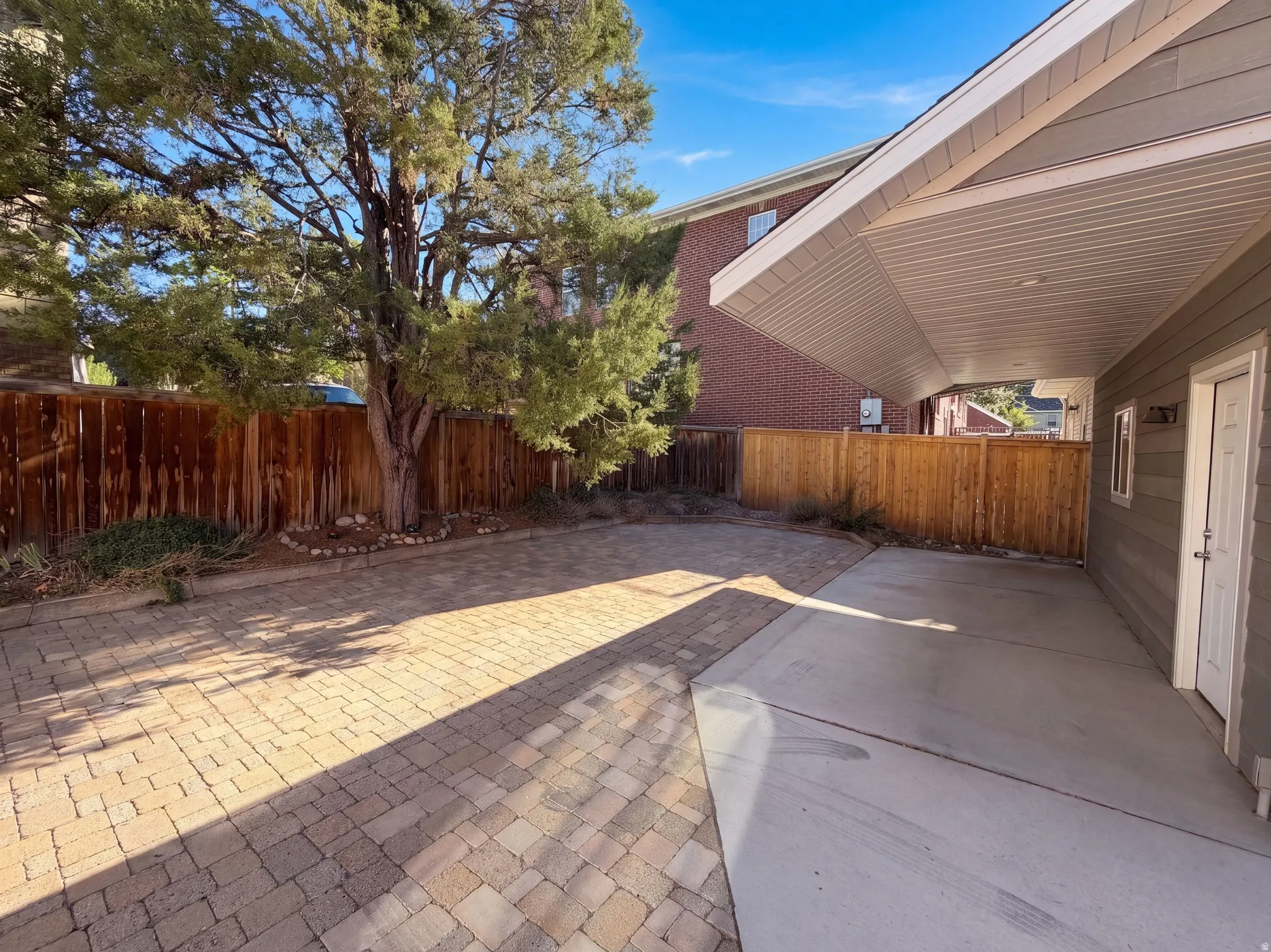 Expansive exterior patio featuring paver stones, concrete surfacing, and a covered section