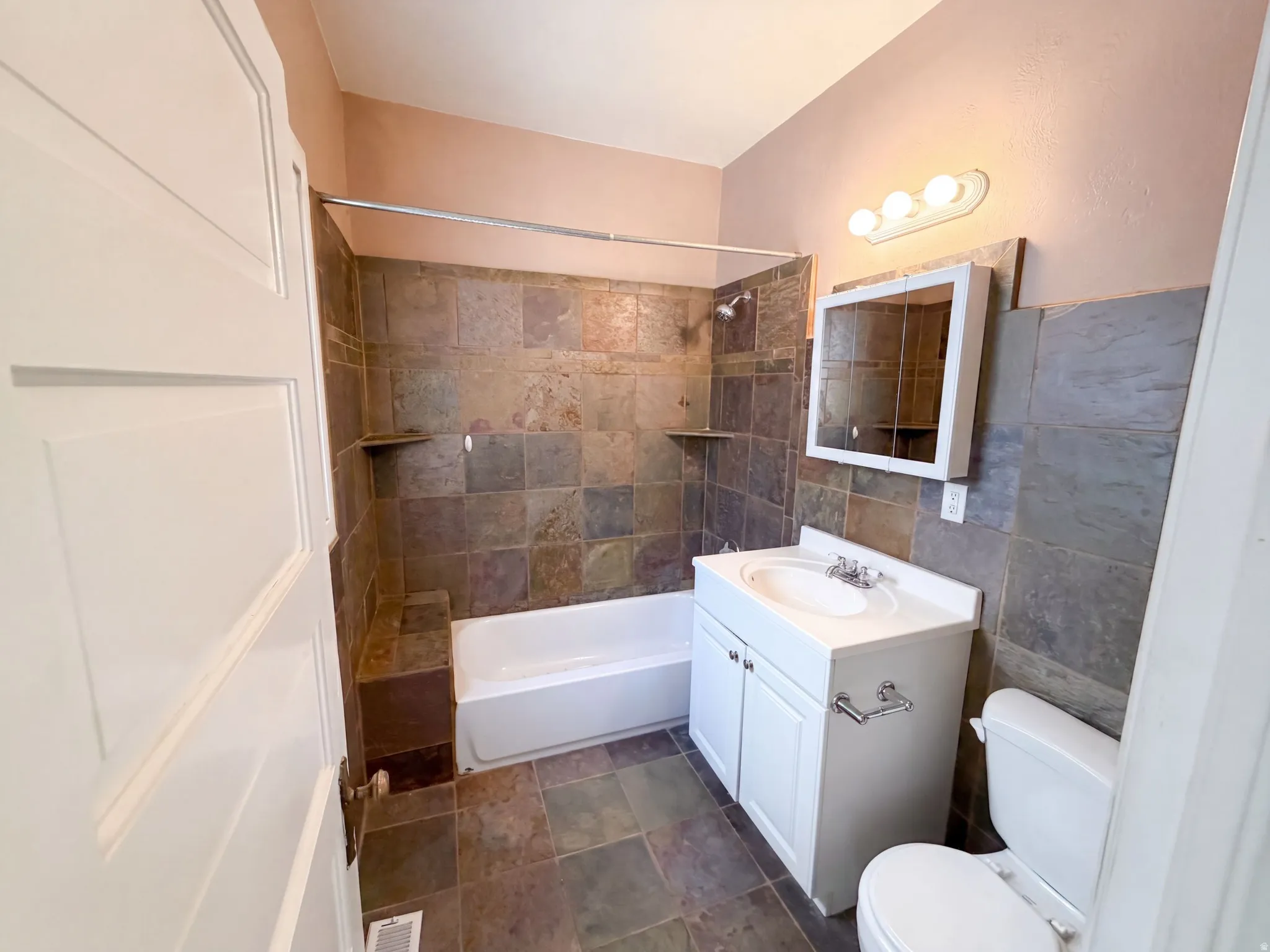 Full bathroom featuring tiled walls, tiled flooring, a built-in tub with shower, and a vanity with an integrated sink