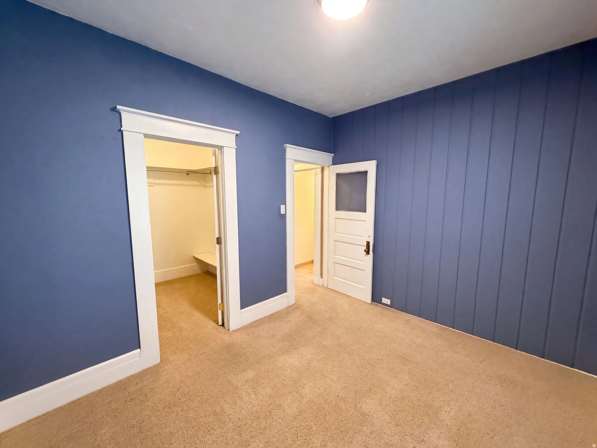 Plank wall paneling with a blue finish, neutral carpeting, and white trim