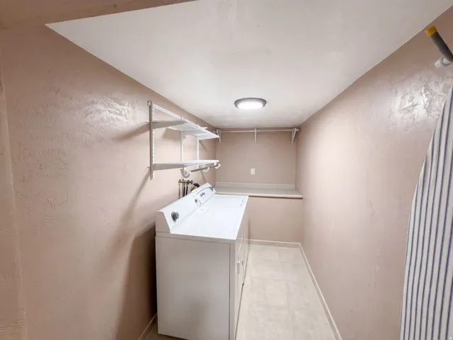 Dedicated utility space featuring a built-in countertop, wall-mounted shelving, and overhead lighting