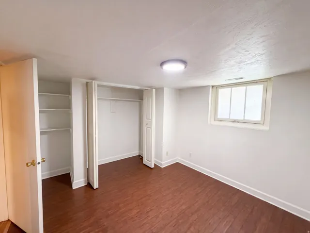 Wood-finish flooring, built-in shelving, closet with bi-fold doors, and a flush mount ceiling light
