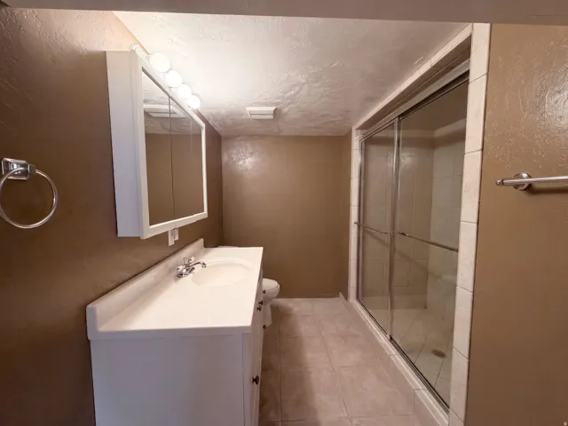 White vanity with integrated sink, chrome faucet, and mirrored medicine cabinet