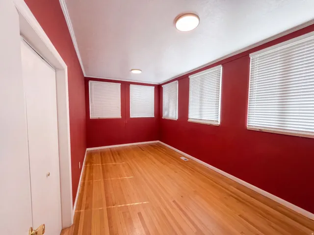 Hardwood flooring, multiple windows with blinds, flush-mount lighting, and bi-fold closet doors