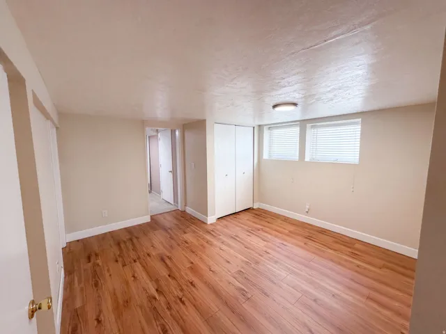 Wood-finish flooring, white walls, two windows with blinds, and built-in closet doors