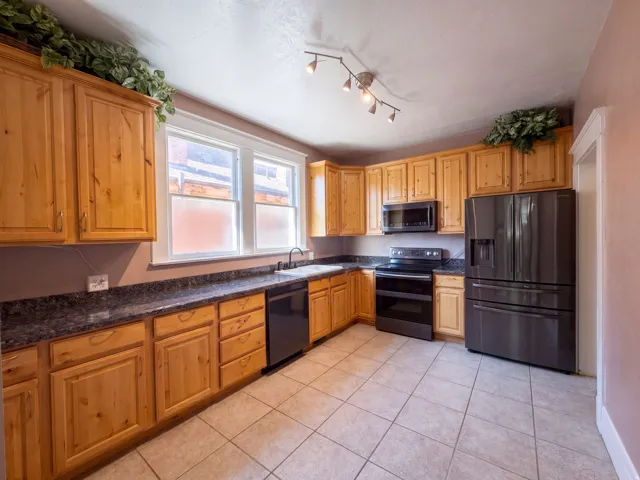 Natural wood cabinetry, dark stone-finish countertops, and stainless steel appliances