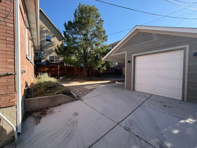 Detached garage with horizontal siding, a white panel garage door, and an attached carport