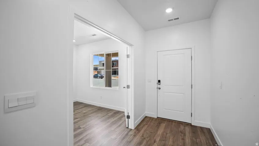Wood-finish flooring, recessed lighting, and a white two-panel door with smart lock hardware
