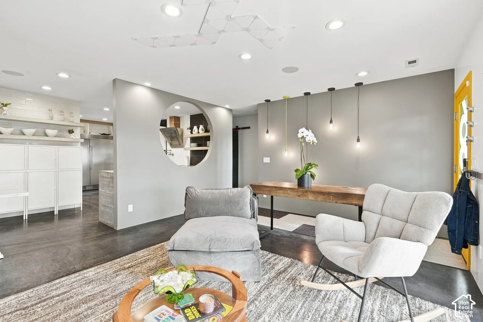 Recessed lighting, wood-finish flooring, custom circular pass-through, pendant lighting, and an accent wall