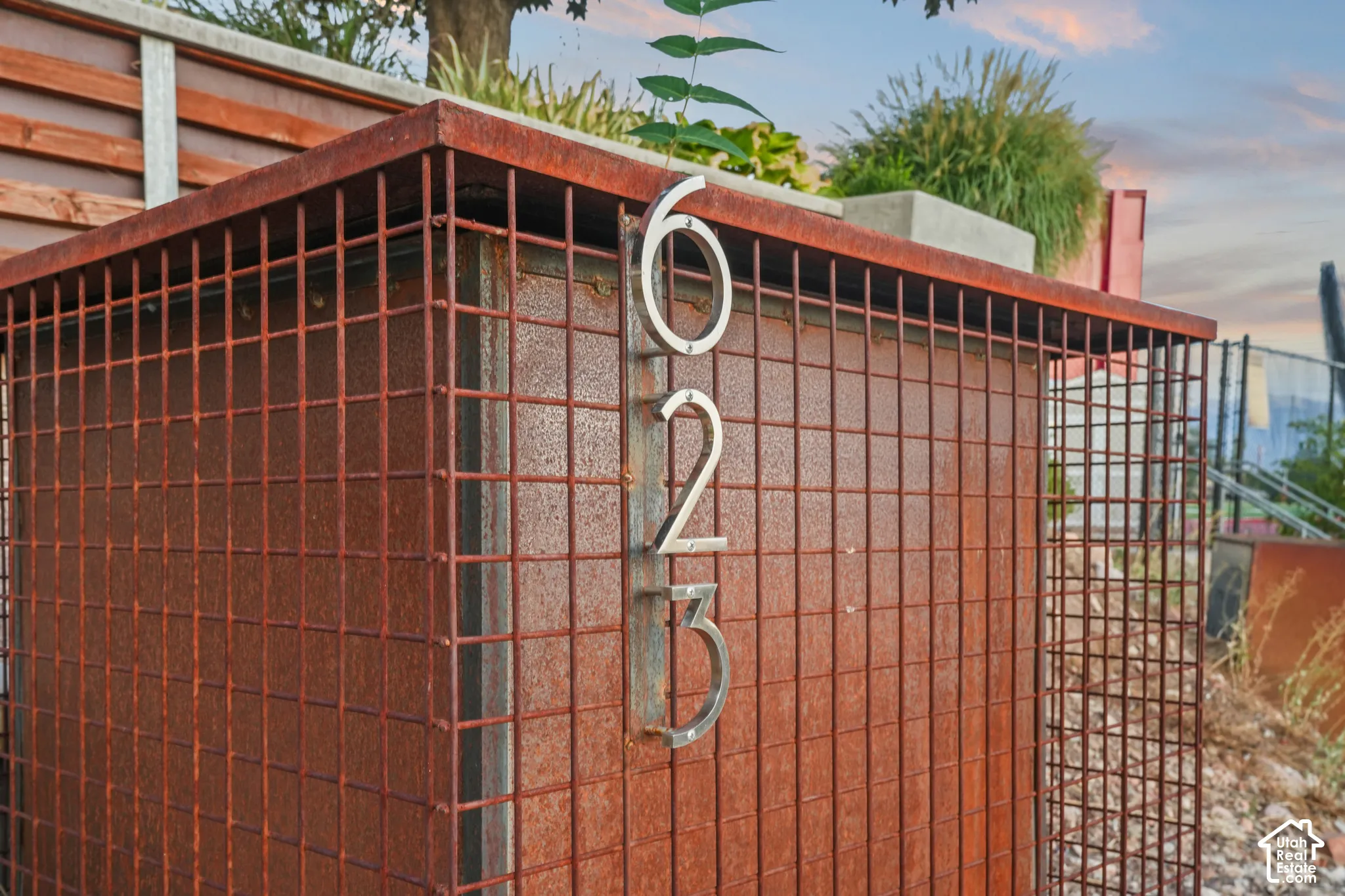 Cor-ten steel mailbox enclosure with a weathered finish, featuring prominent silver-tone address numbers