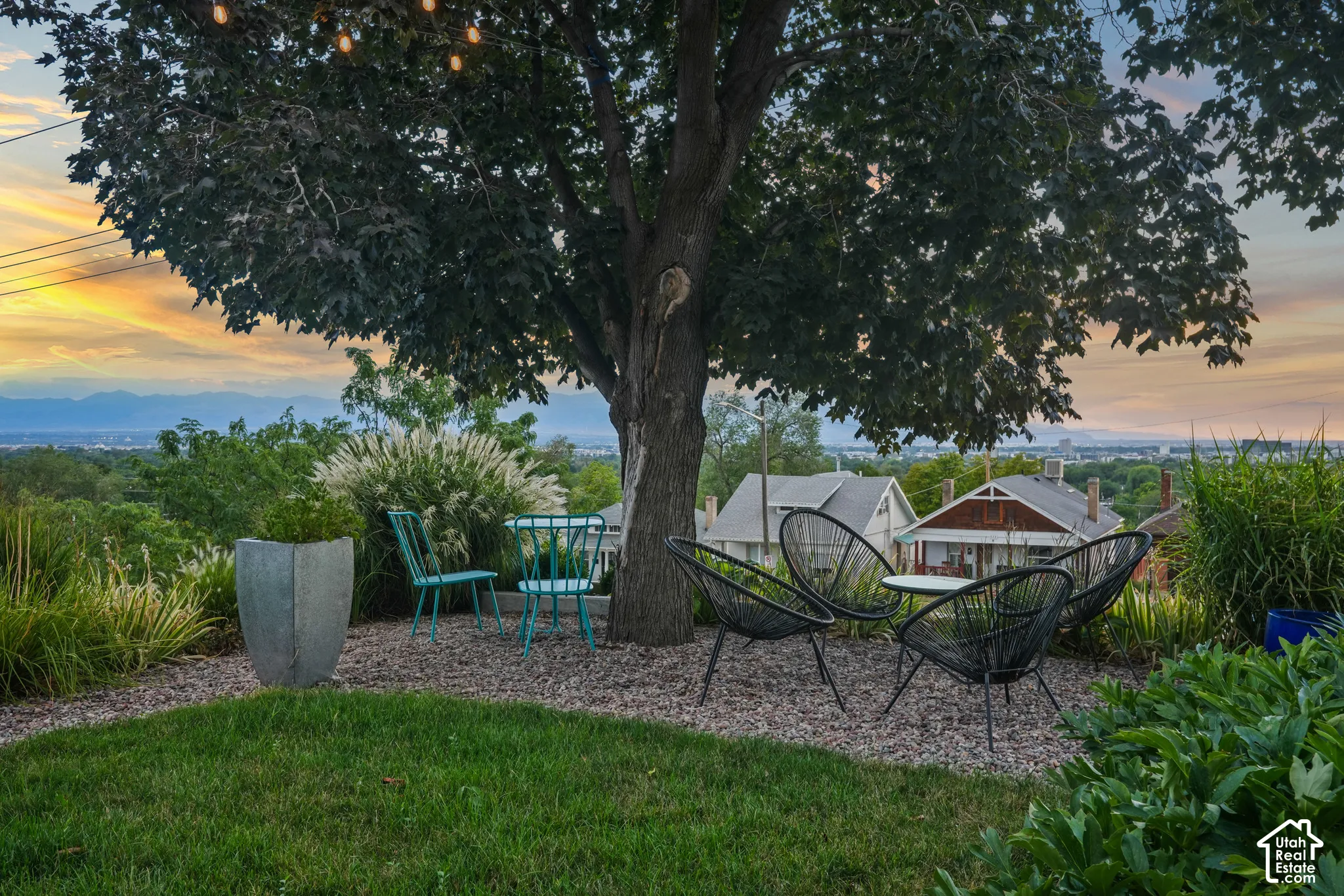 Landscaped outdoor area featuring a mature tree, string lighting, and gravel hardscaping