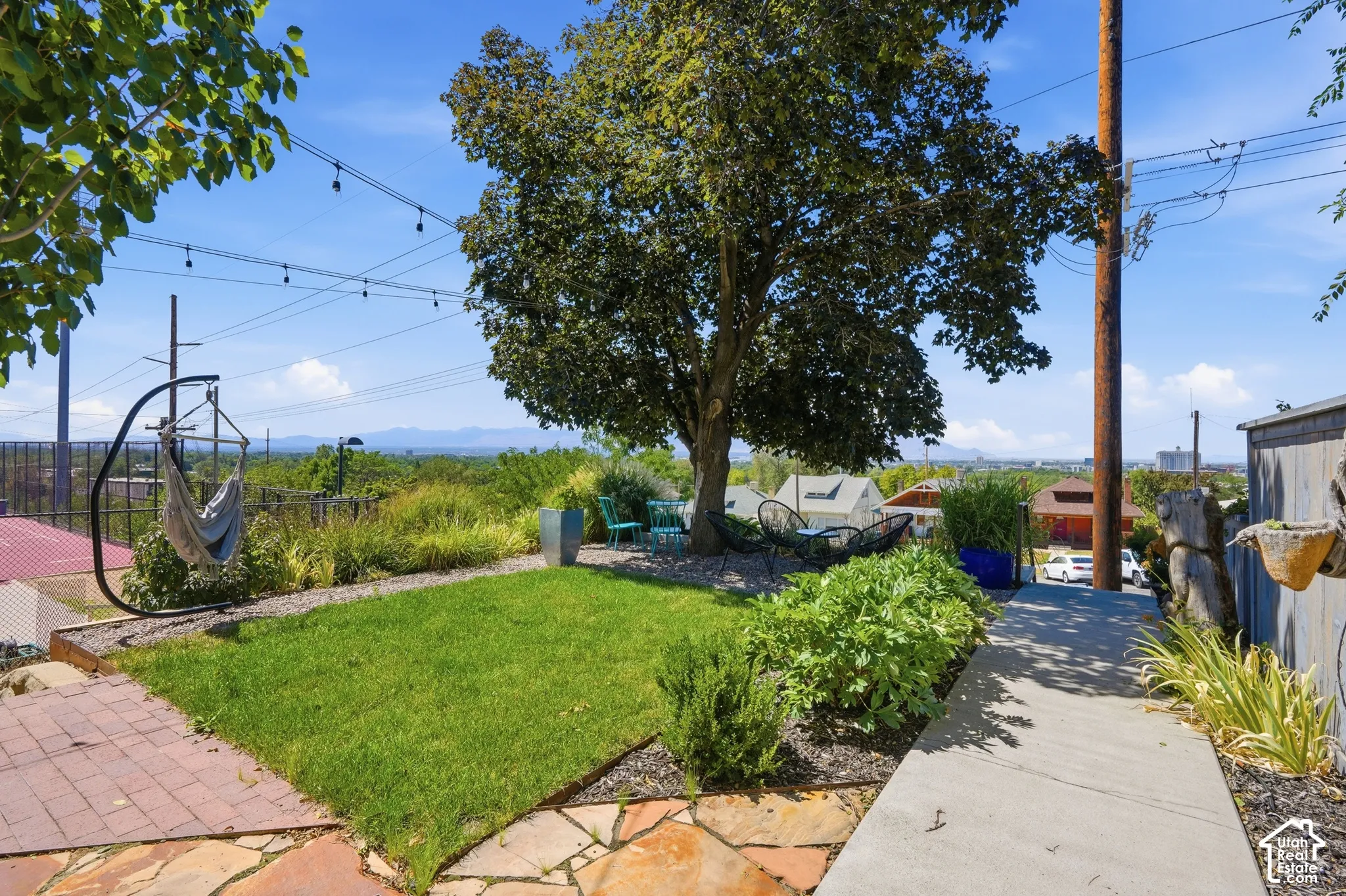 Landscaped yard with a manicured lawn, established tree, and paved pathways