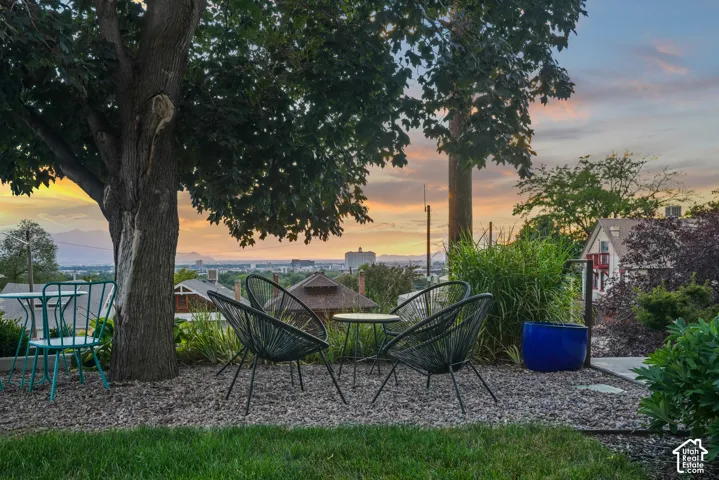Tiered yard with established trees, gravel patio, and concrete stepping stones