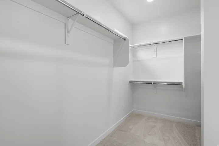 Spacious walk-in closet featuring dual clothing rods, multiple shelving units, and neutral finishes throughout