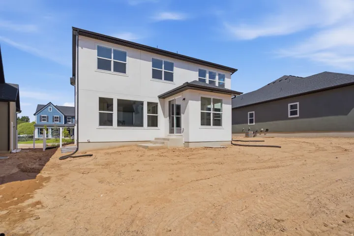 Modern two-story residence featuring a clean-lined white exterior with multiple windows, black trim accenting, and a covered entry portico