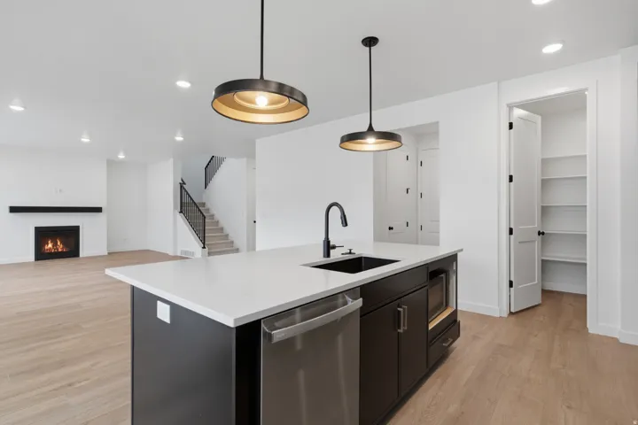 Modern kitchen island featuring stainless steel appliances, white quartz countertops, and black cabinetry with a waterfall edge