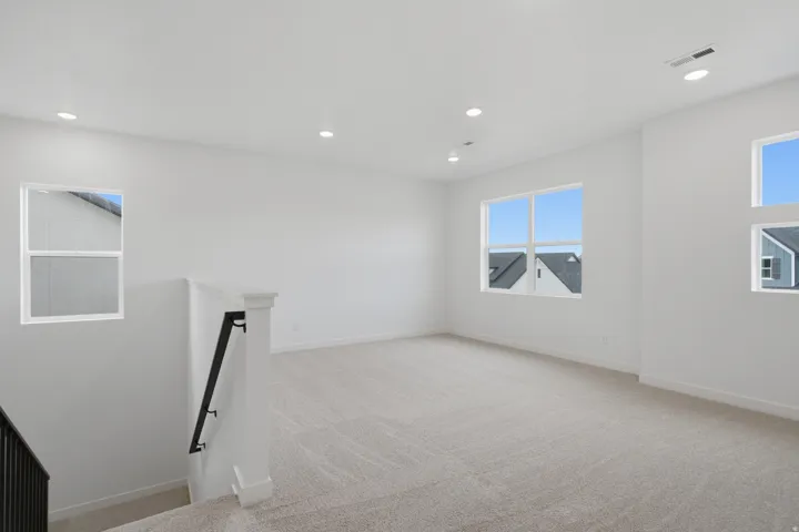Expansive open space with multiple windows, recessed lighting, and carpet flooring