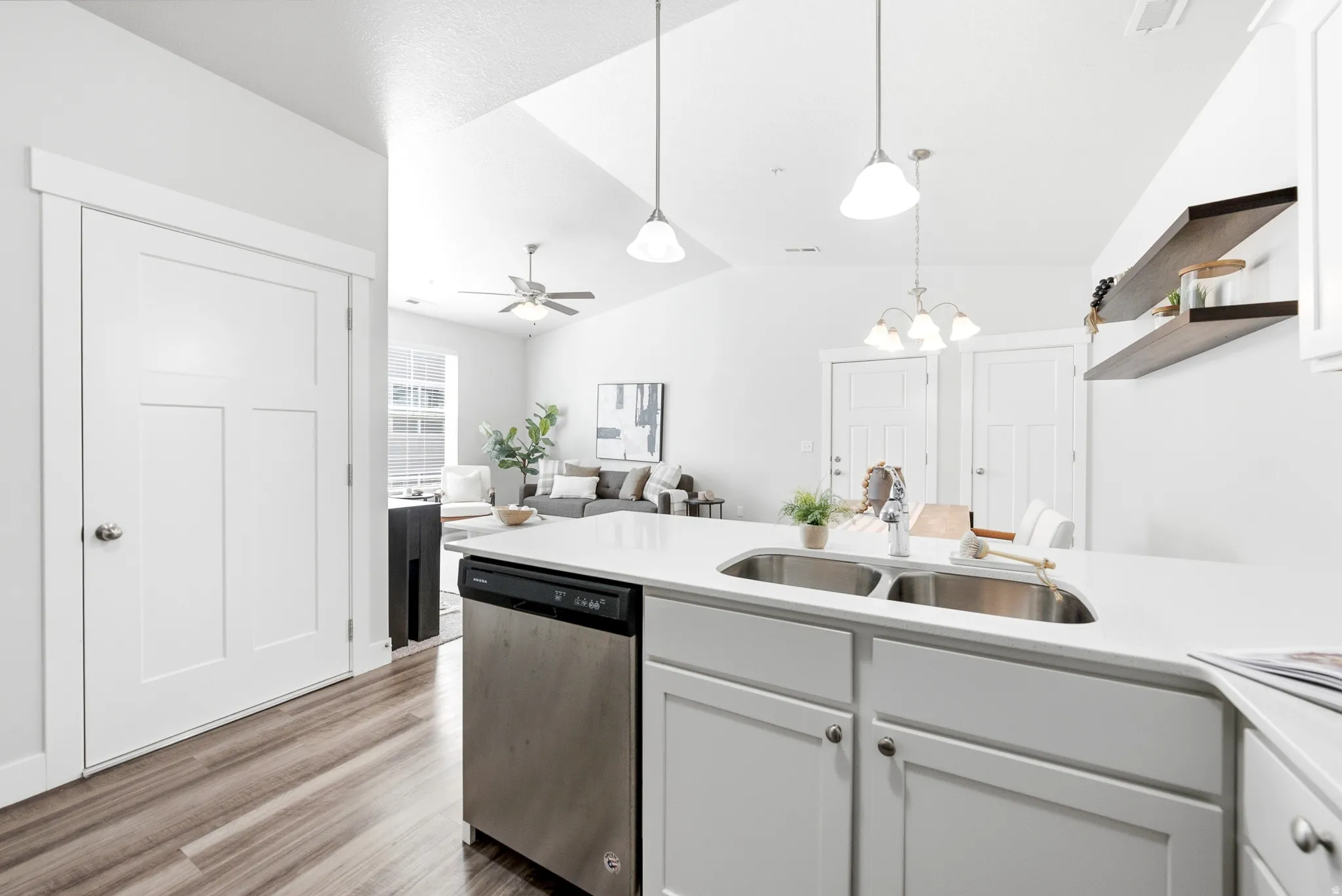 Modern kitchen featuring white cabinetry, stainless steel appliances including a dishwasher, and a large center island with an undermount sink