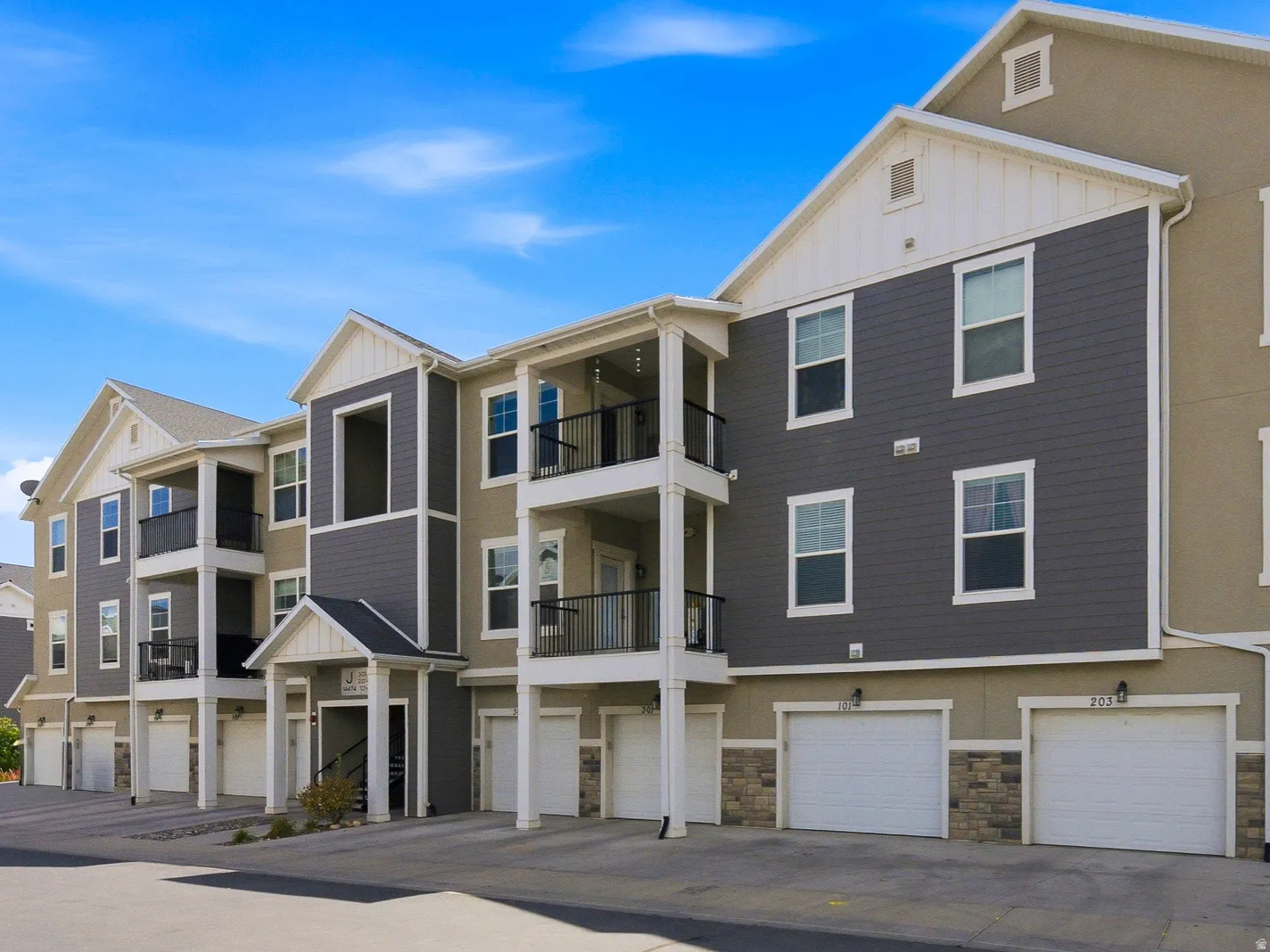 Multi-story structure with a contemporary exterior featuring balconies, an entryway, and multiple garage doors