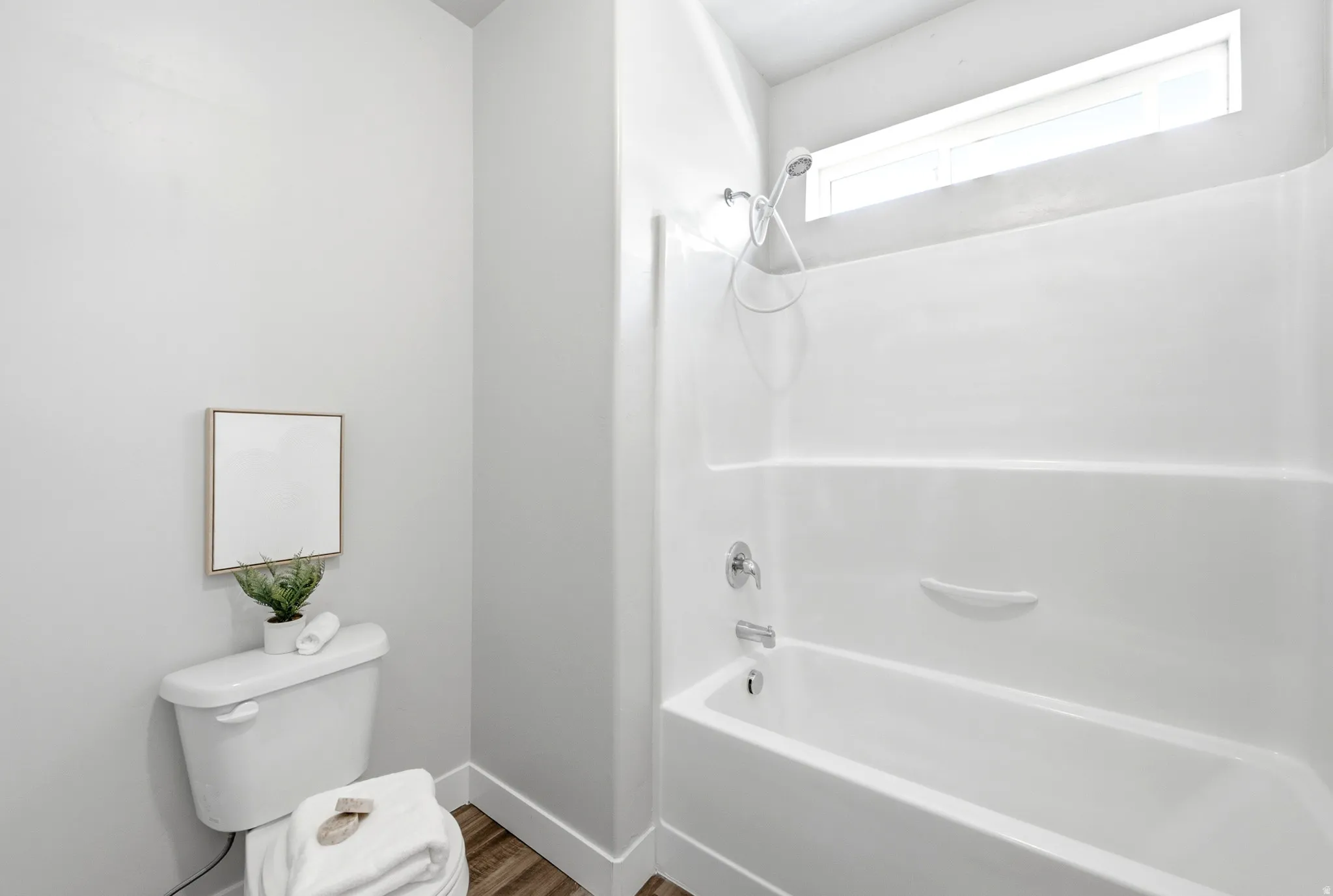 Clean and bright bathroom featuring a white subway tile shower surround with integrated shelf, chrome fixtures, and a pedestal sink