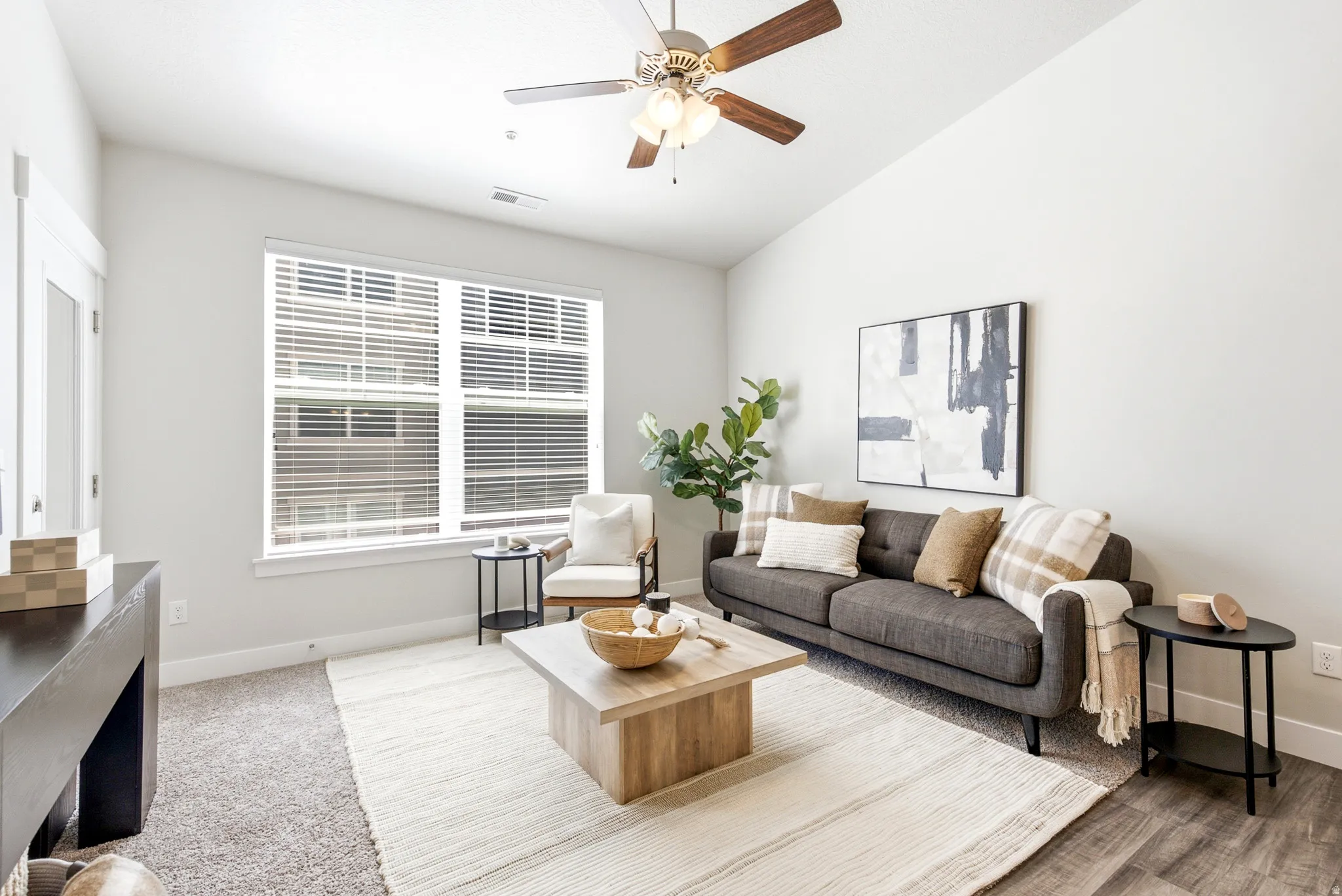 Vaulted ceiling, ceiling fan, large window with blinds, wood-finish flooring, and carpeted area