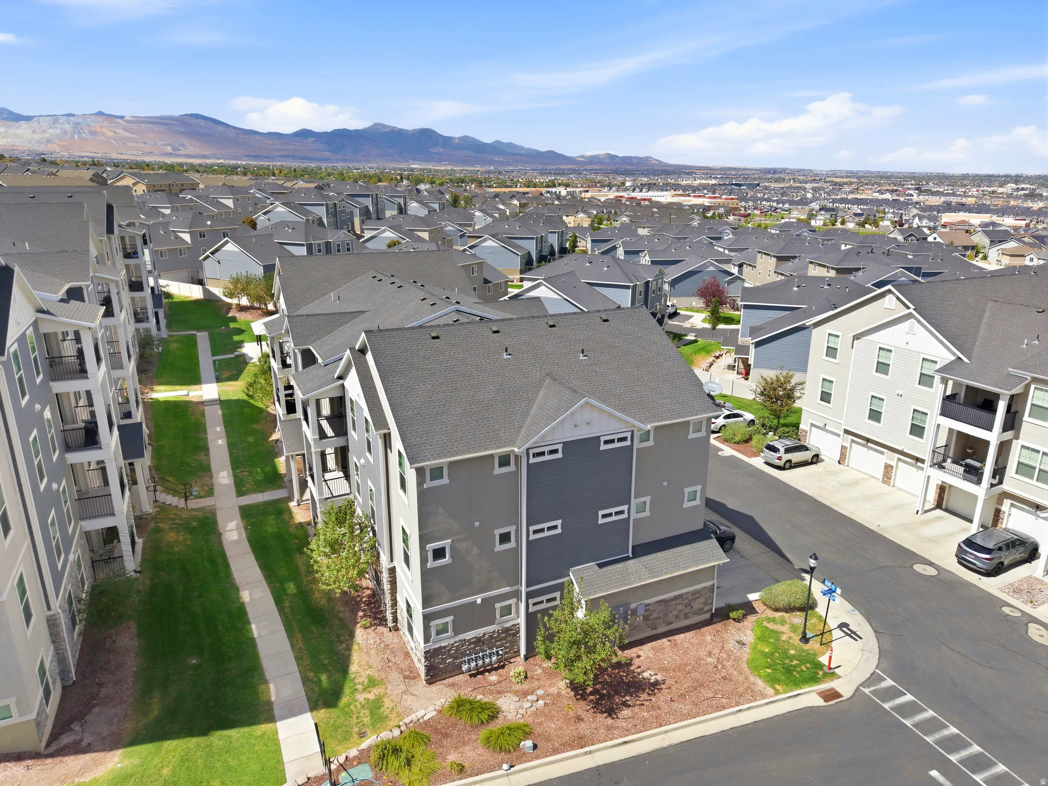 Aerial view of a modern residential community featuring contemporary multi-unit homes with charcoal and neutral exterior finishes, clean architectural lines, and manicured landscaping