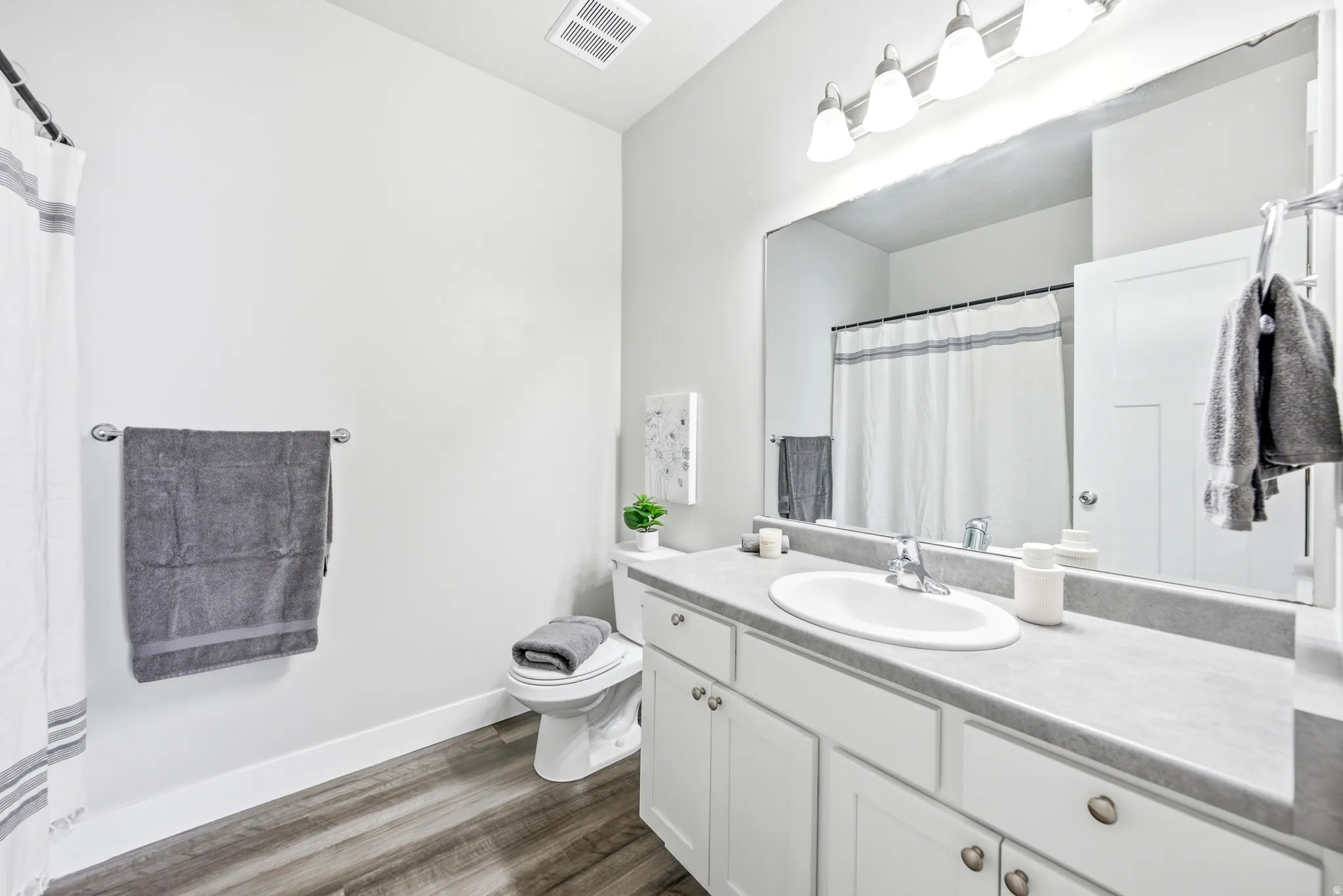 Modern bathroom featuring a white vanity with dual sinks, quartz countertop, and polished chrome fixtures
