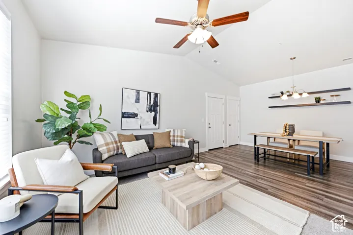 Open-concept living area featuring wood-finish flooring, a ceiling fan with integrated lighting, and abundant natural light