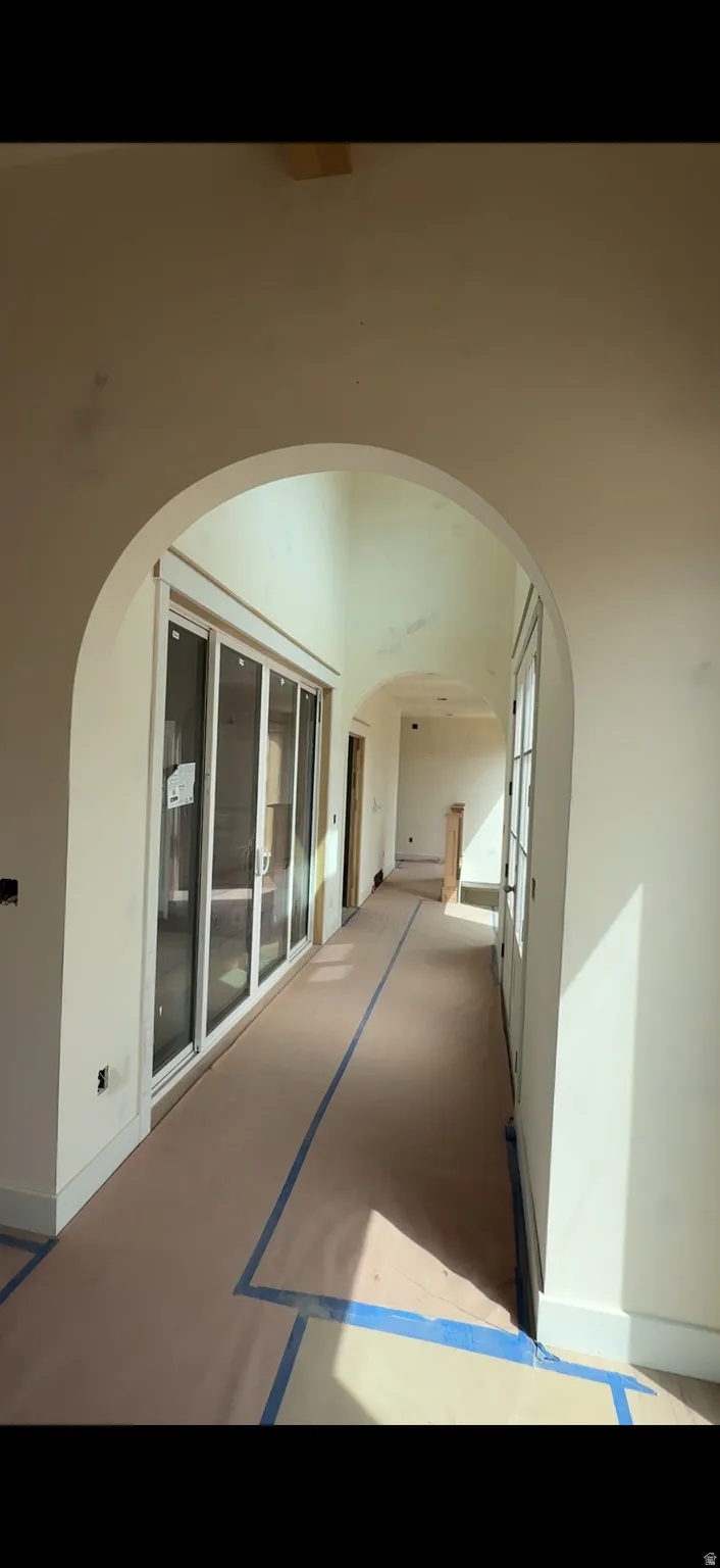 Arched entryway with a long hallway, featuring a wall of multi-panel glass doors