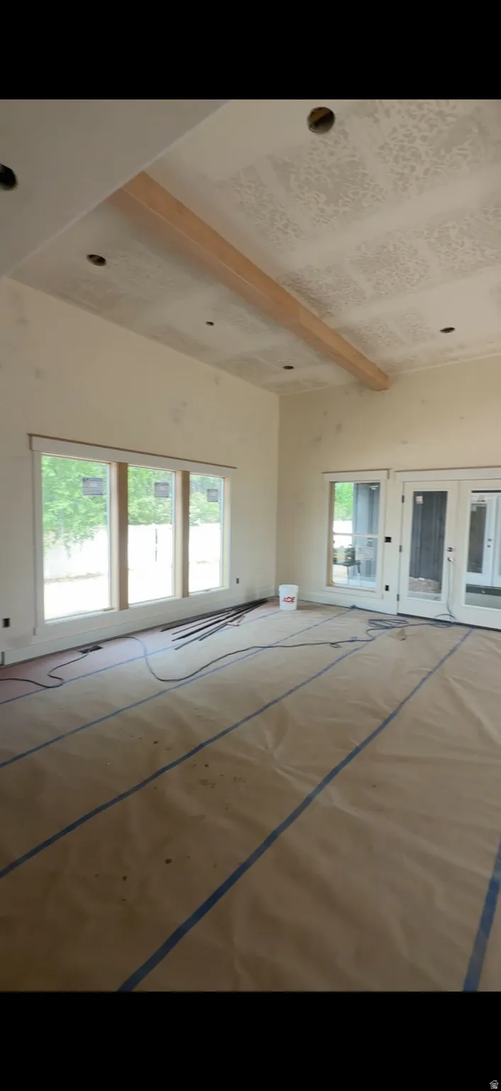12 Ft ceiling with a wood beam accent, recessed lighting, expansive windows, and French doors