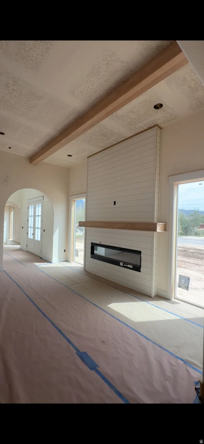 Great room with a shiplap fireplace surround,(will be painted black) built-in linear fireplace, wood mantel, and exposed ceiling beam