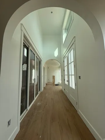 High ceilings, arched doorways, light wood-finish flooring, transom windows, and white interior doors