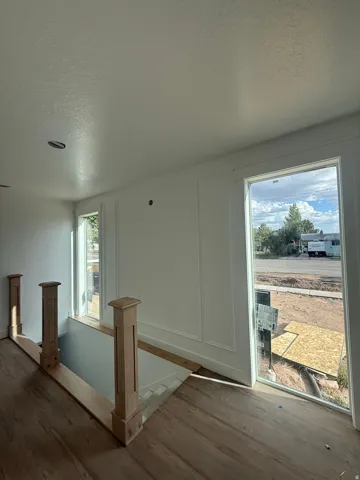 Wood-finish flooring, white paneled wall accents, and large windows