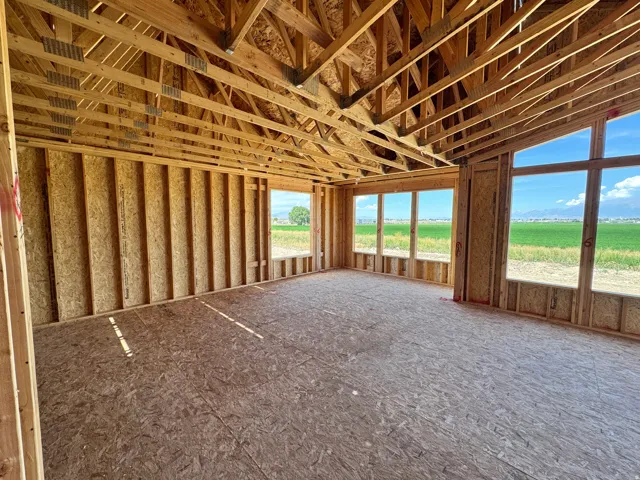Open-concept framing with exposed roof trusses, extensive window placements, and expansive plywood subflooring