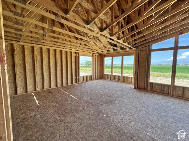 Open-concept framing with exposed roof trusses, extensive window placements, and expansive plywood subflooring