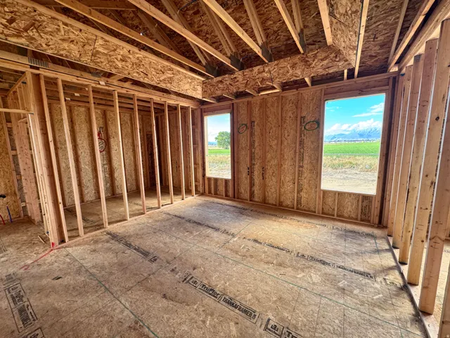 Vaulted ceiling framing, exposed wall studs, and two window openings