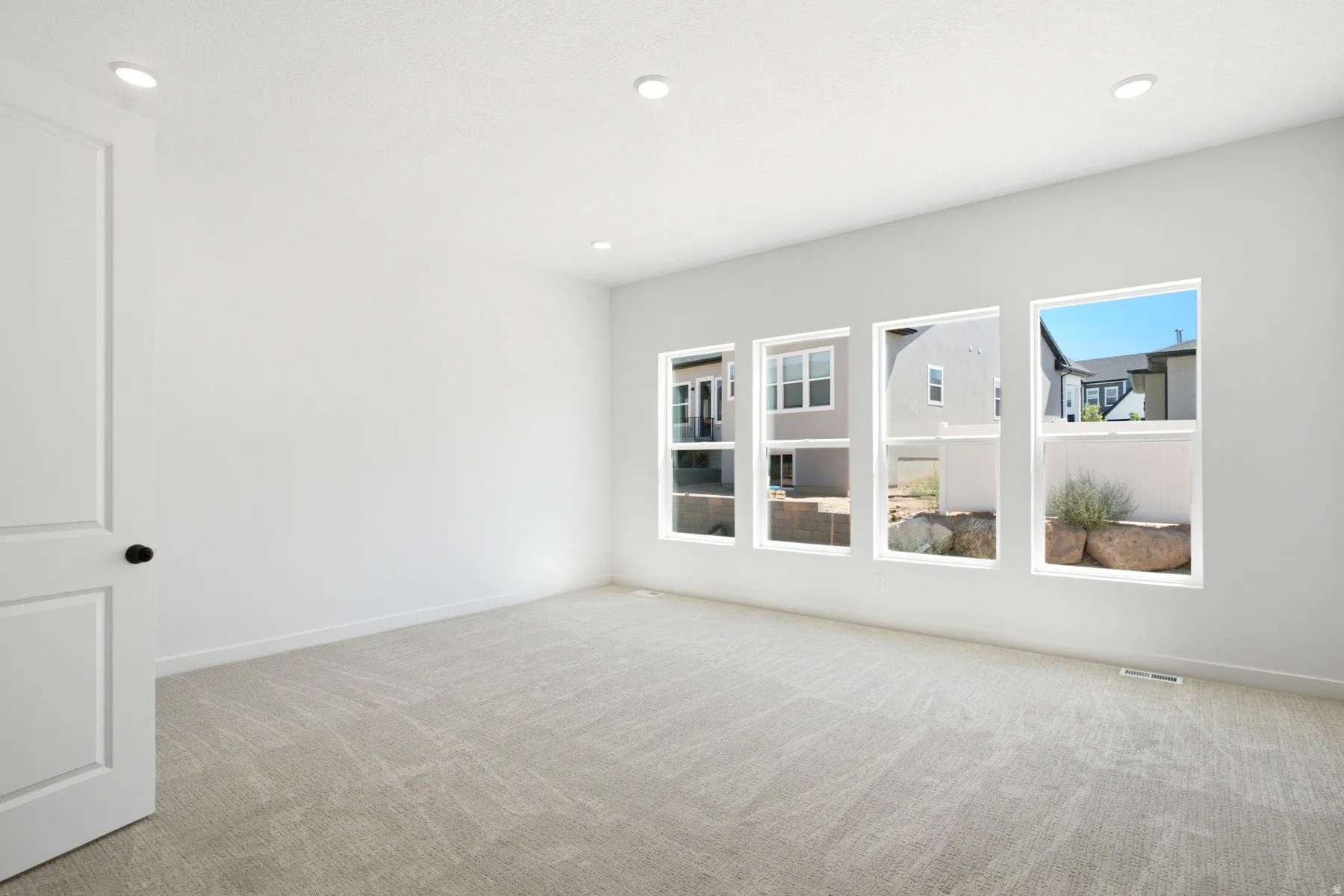 White walls with recessed lighting, light-toned carpet, and a series of four rectangular windows