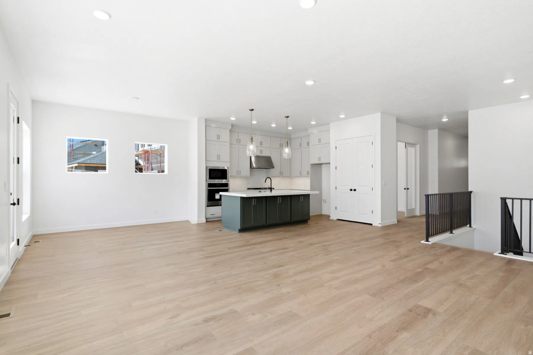 Open-concept living area featuring wood-finish flooring, recessed lighting, and a modern kitchen with a large island